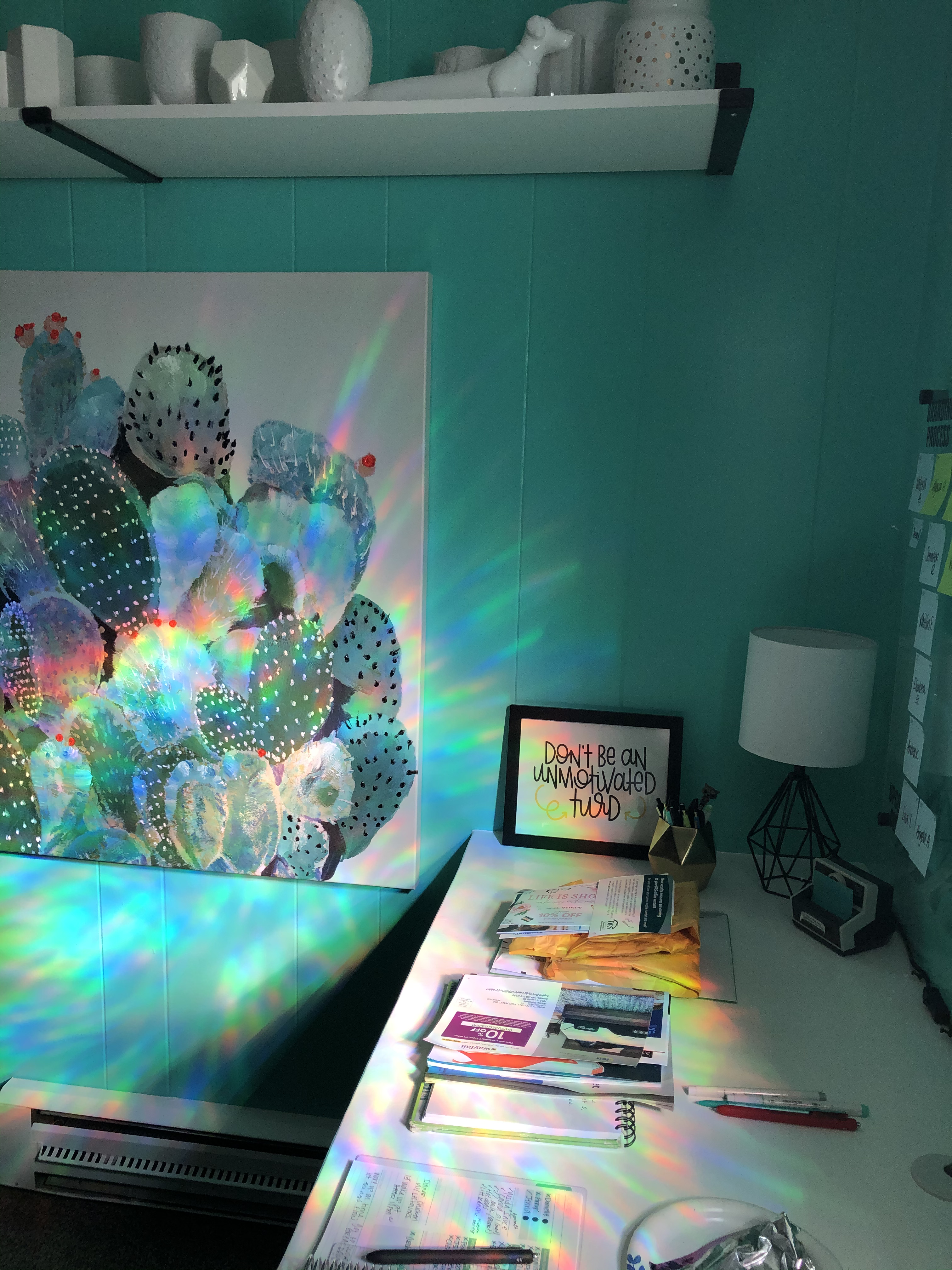Rainbow window film projecting on the teal walls of my office